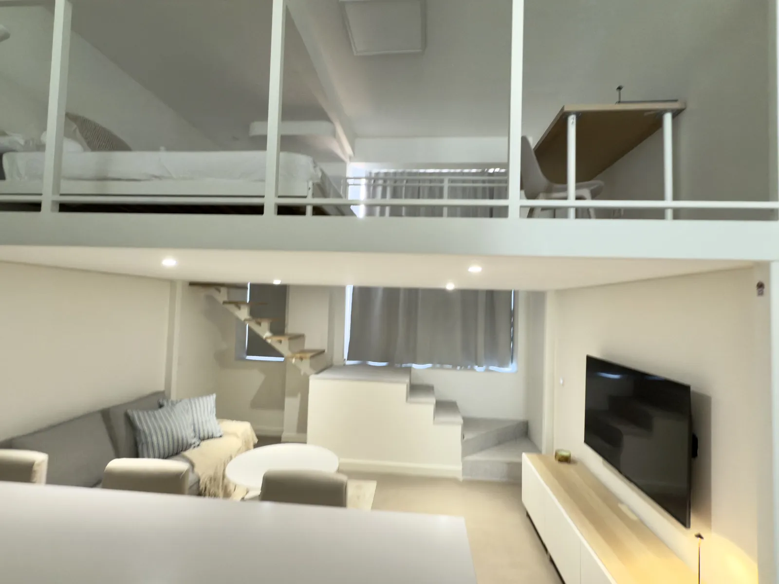 Vista del altillo dormitorio sobre un salón con sofá y escalera lateral