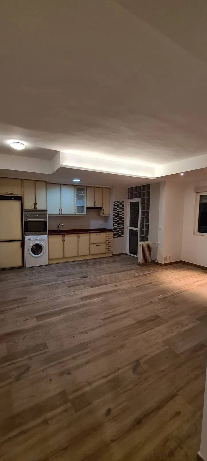 Salón con suelo porcelánico imitación madera y techo con luz indirecta