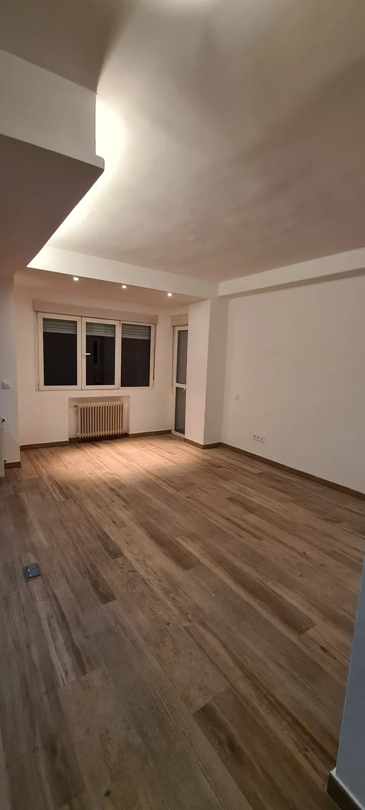 Estancia pintada en blanco con suelo imitación madera junto a la ventana