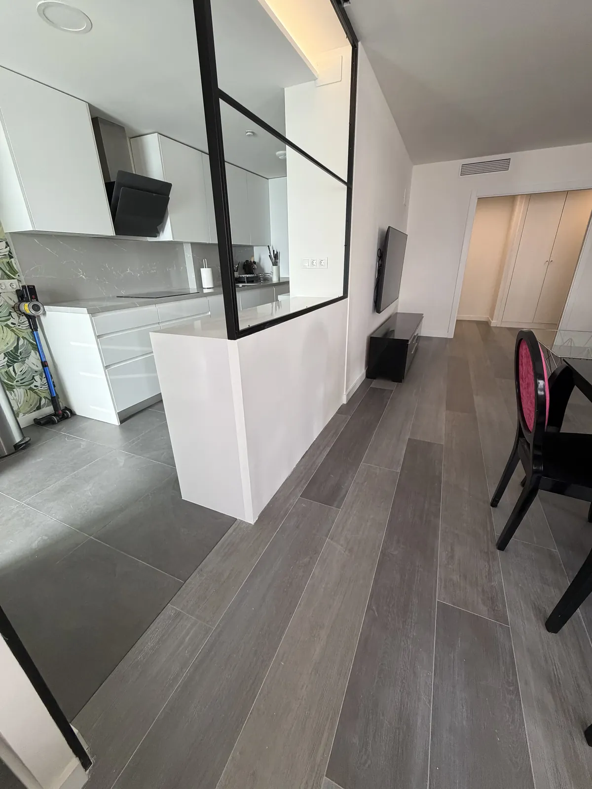 Península blanca de cocina con cerramiento de vidrio y pasillo con suelo gris