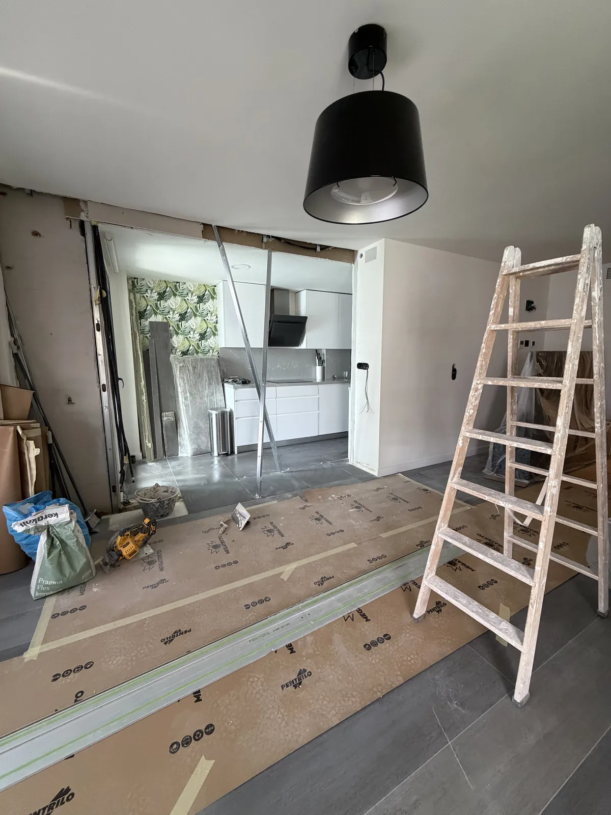 Obra en curso: suelo protegido y escalera durante la apertura entre cocina y salón