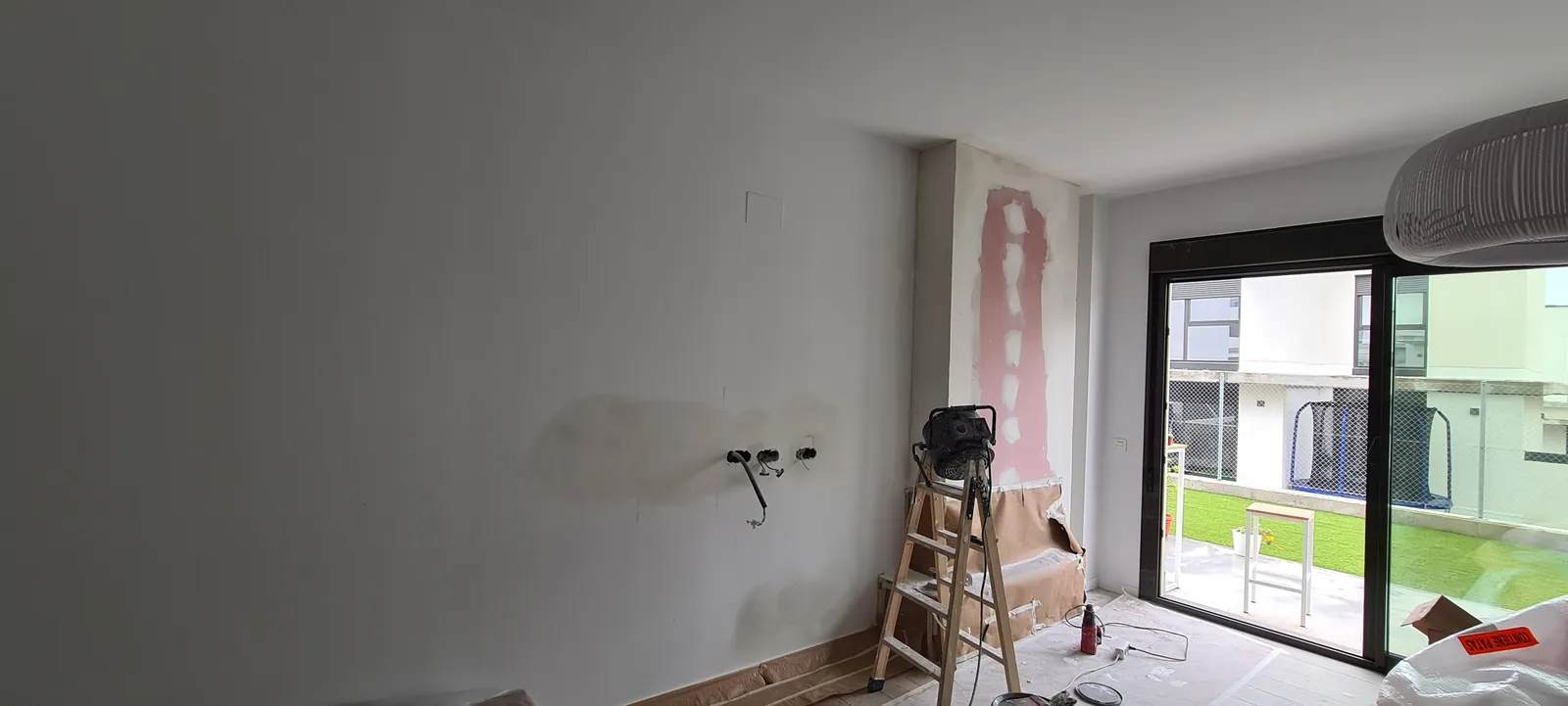 Salón antes de instalar la chimenea, con pared lisa y obra en curso