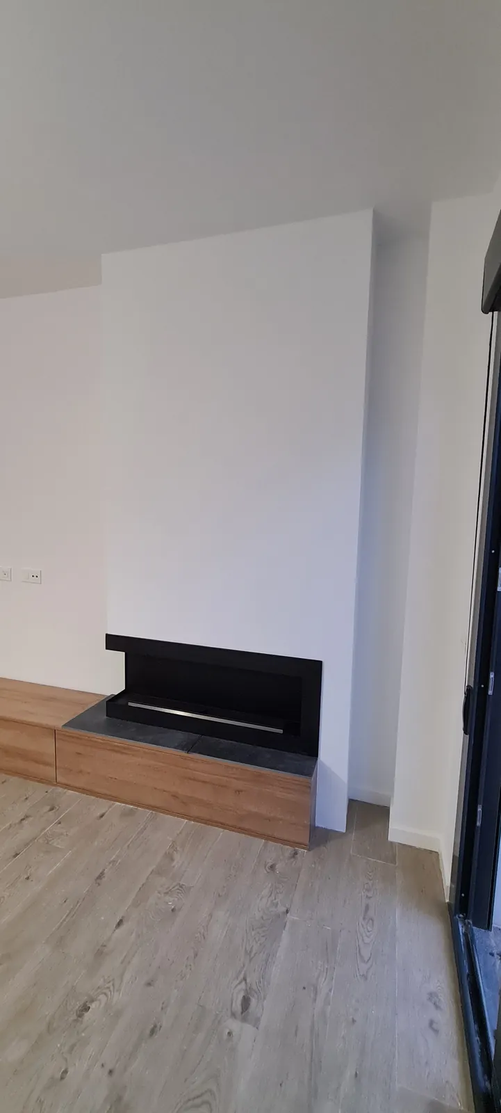 Detalle de chimenea empotrada sobre banco de madera y suelo laminado claro