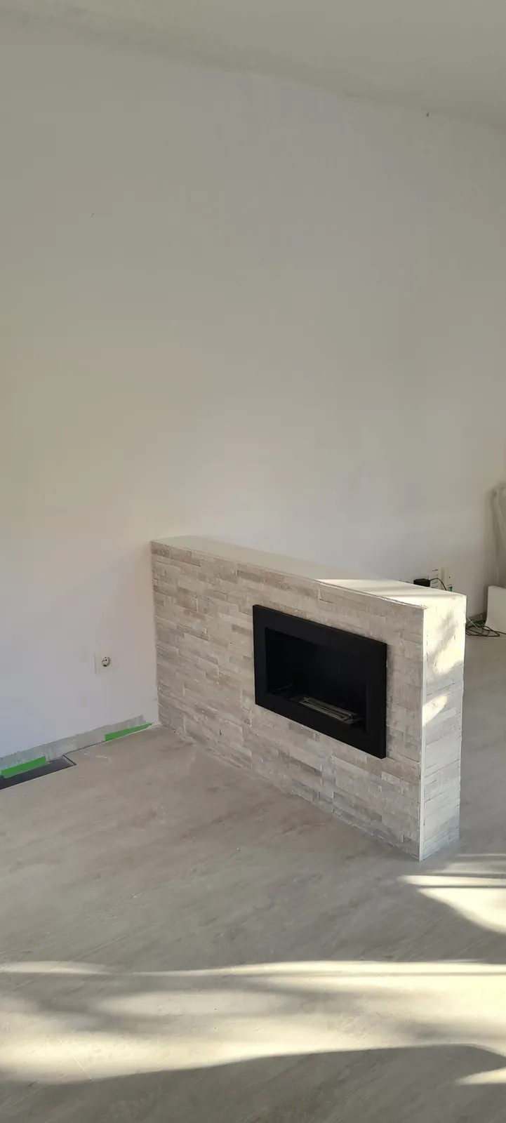 Chimenea con revestimiento tipo piedra claro y hogar empotrado en el salón