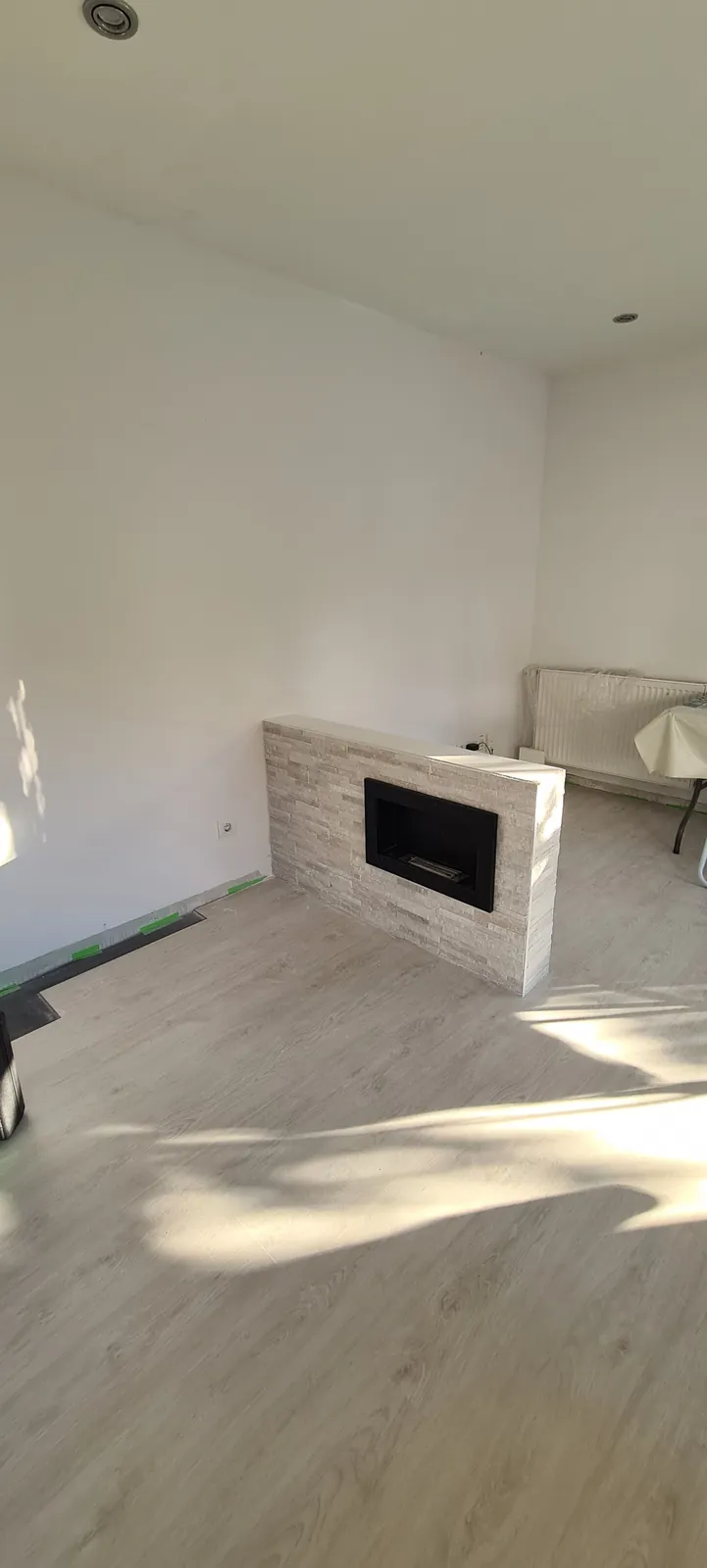 Mueble-chimenea revestido en piedra clara visto desde el salón