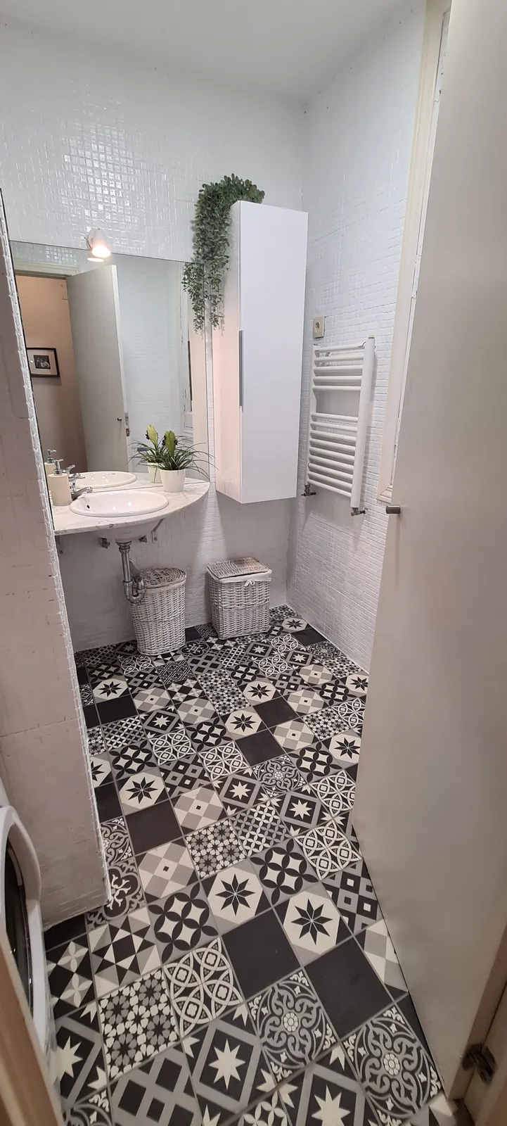 Baño con suelo de baldosa geométrica blanca y negra y lavabo blanco