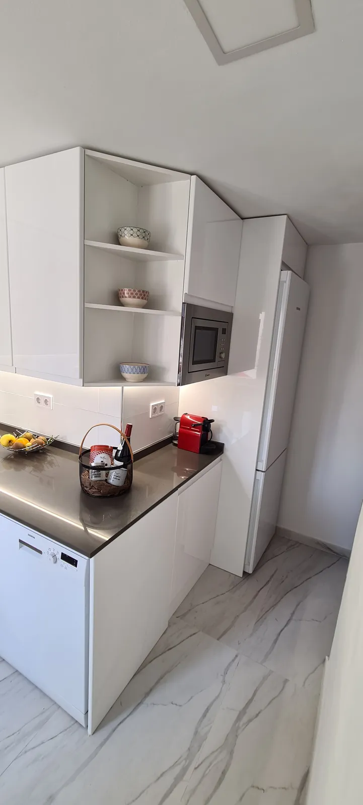 Esquina de cocina con estantes abiertos, microondas integrado y encimera gris