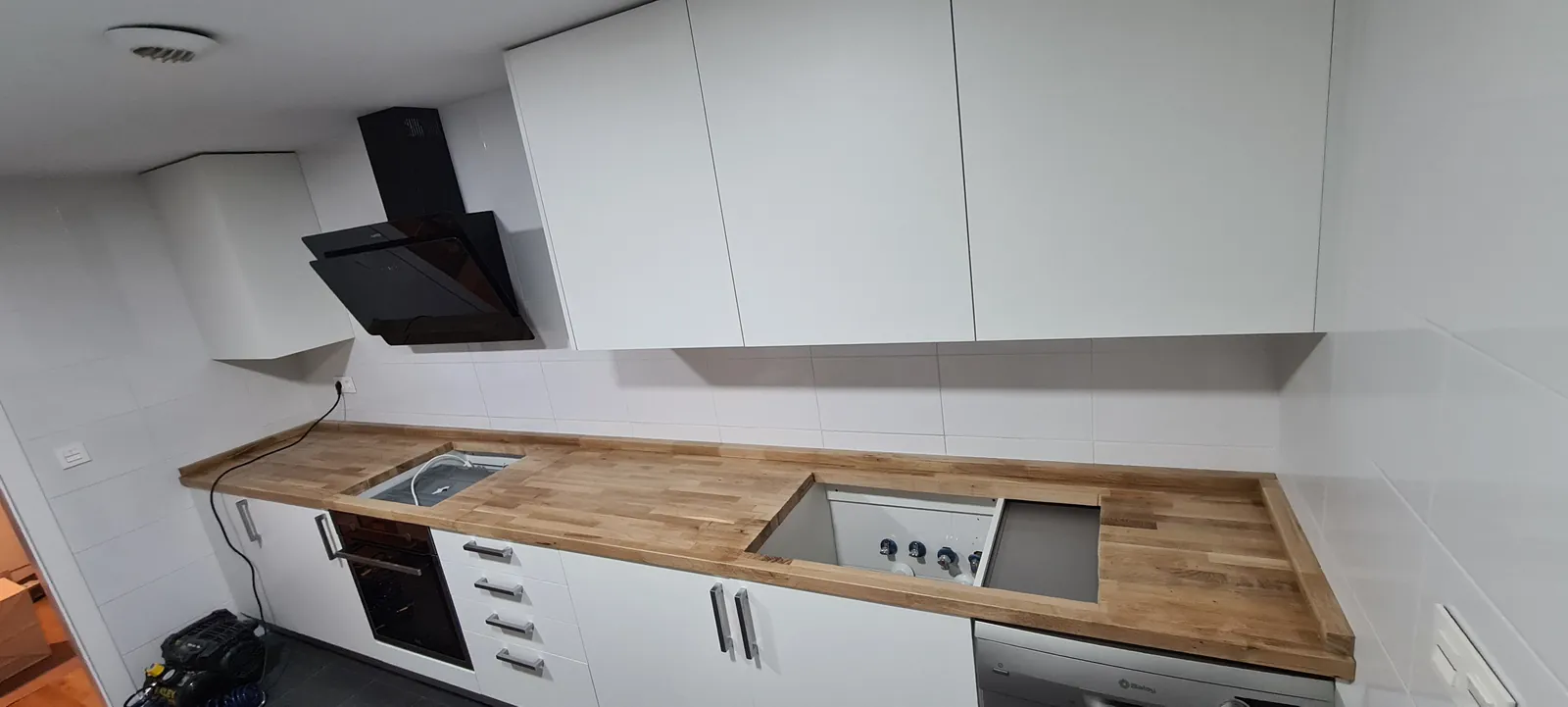 Encimera de madera con fregadero y placa integrados en cocina blanca