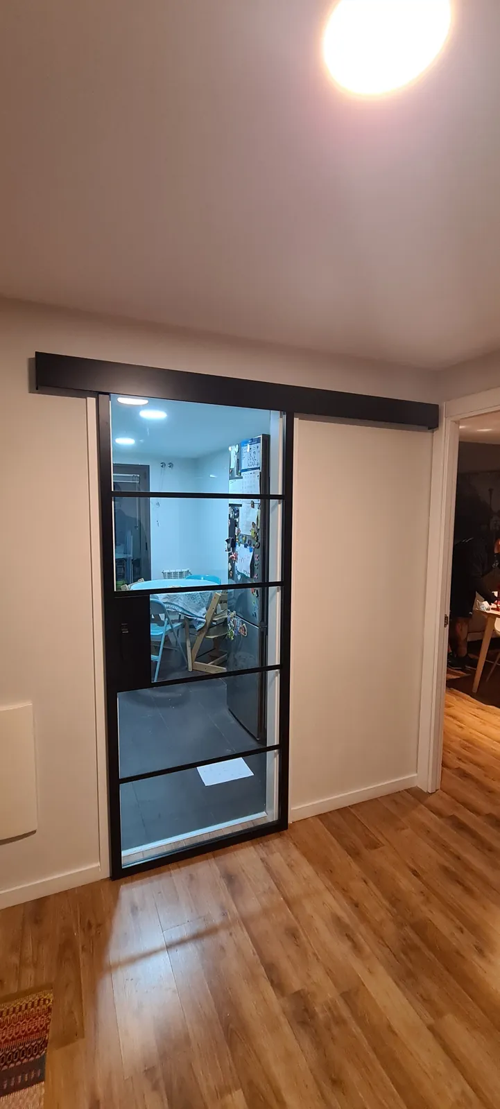 Puerta corredera acristalada de estilo industrial junto a suelo de madera