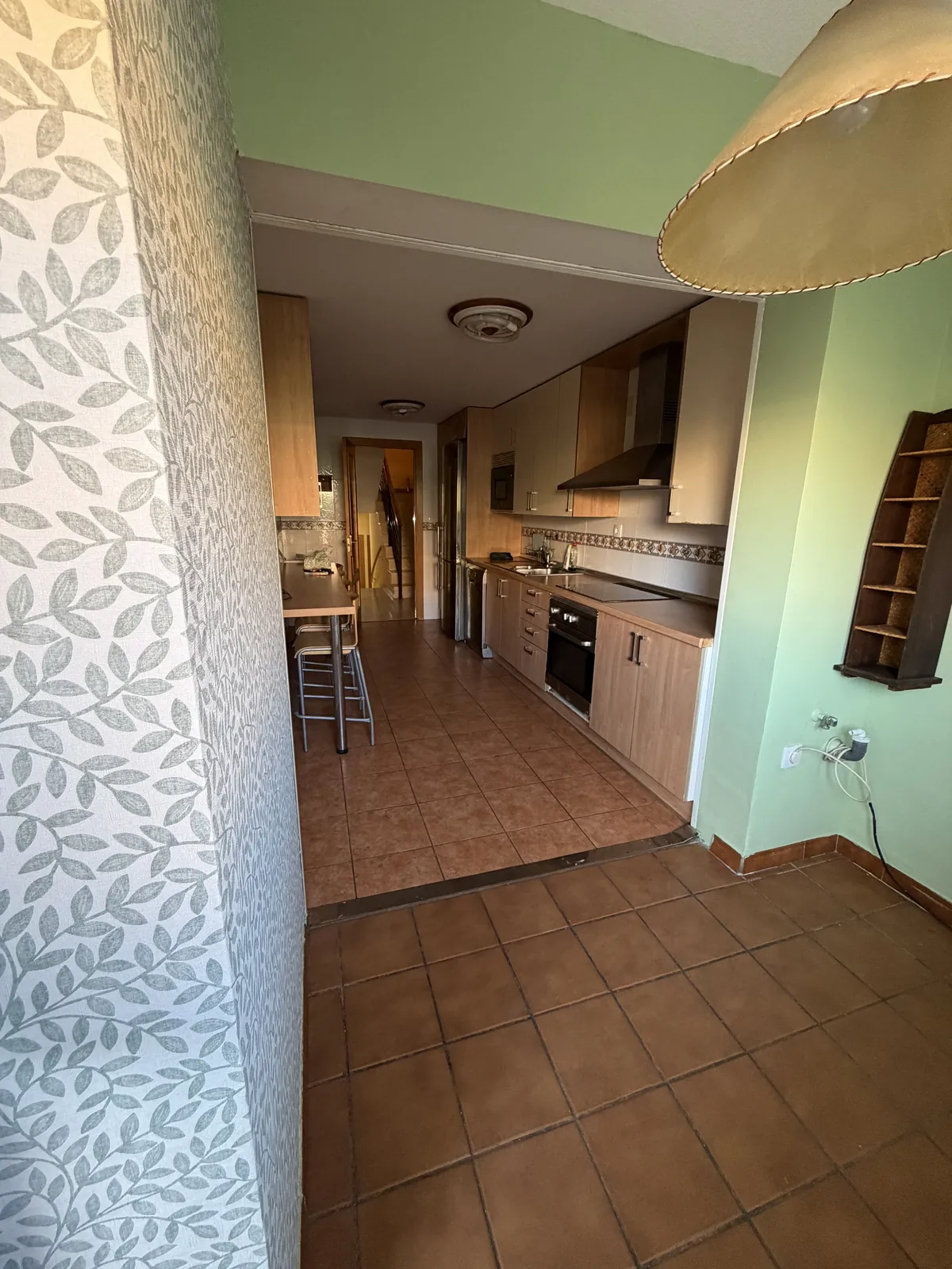 Cocina antes de la reforma con suelo de baldosa terracota y muebles antiguos