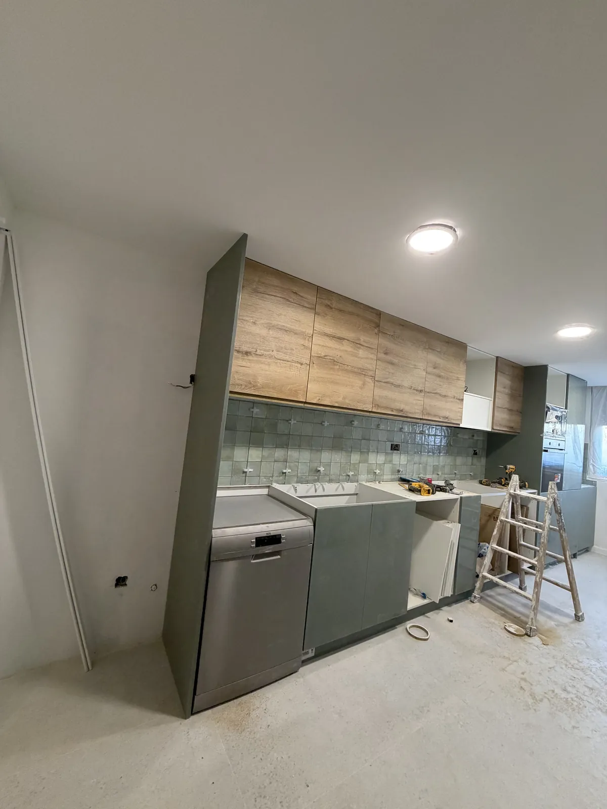 Columna y muebles bajos verdes con lavavajillas integrado durante el montaje de la cocina
