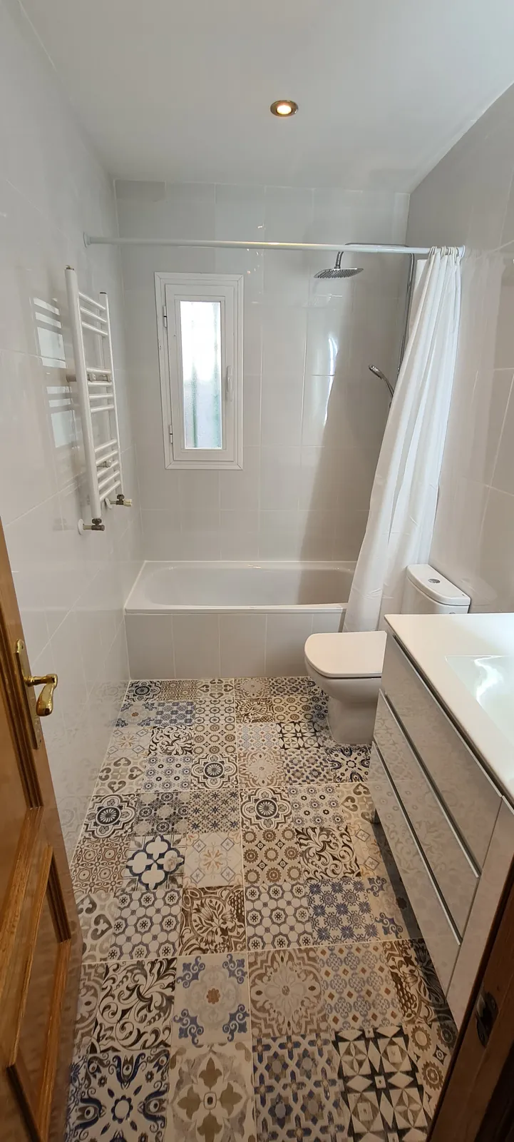 Baño con bañera, alicatado blanco y suelo de baldosa hidráulica azul