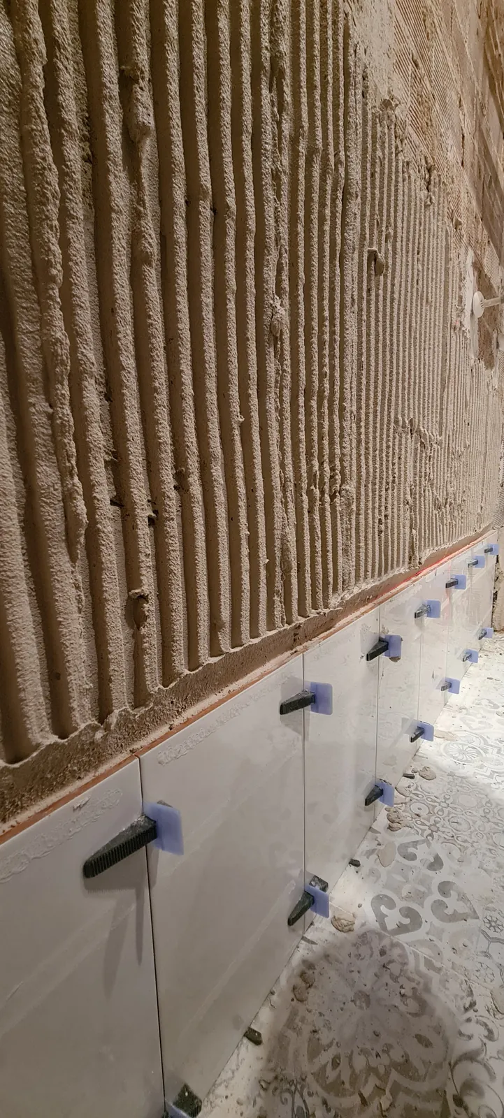Colocación del nuevo alicatado sobre pared preparada con cemento cola