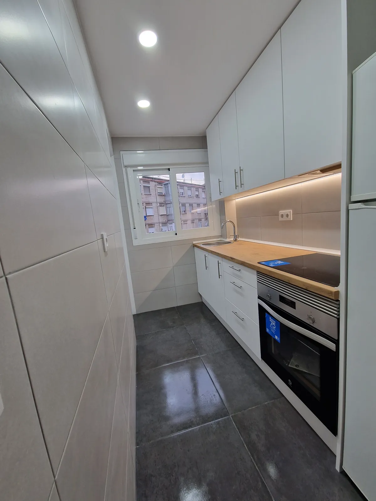 Cocina en paralelo con columna de horno, encimera de madera y suelo gris oscuro