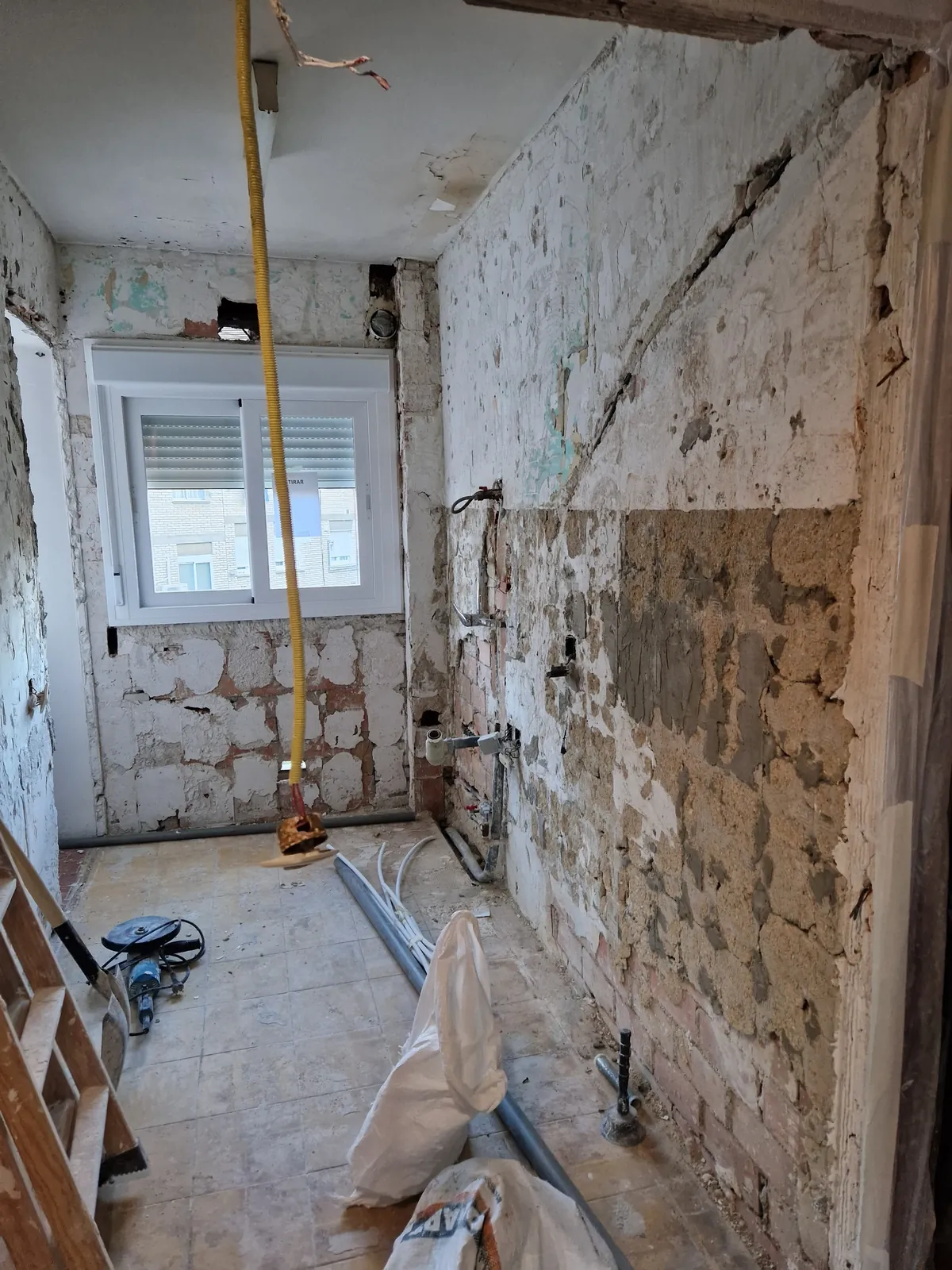 Cocina en demolición con paredes picadas e instalaciones a la vista