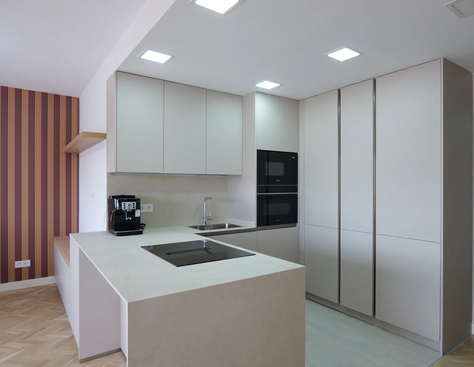 Cocina en forma de península con encimera clara, placa de inducción, armarios columna y horno integrado