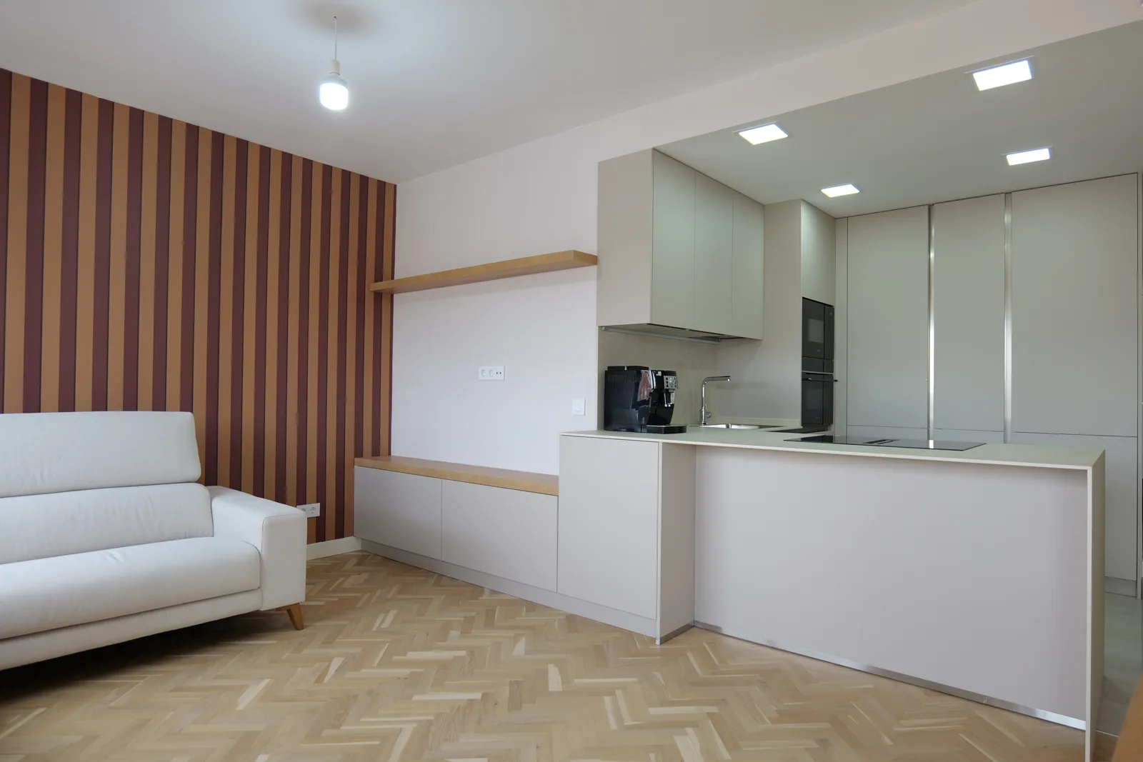 Cocina abierta con barra, mueble bajo con balda de madera y techo con focos empotrados