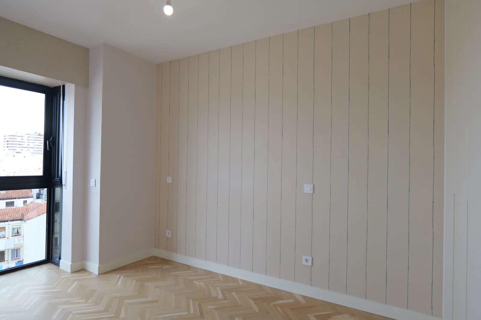 Dormitorio con pared revestida de friso vertical y suelo de madera en espiga