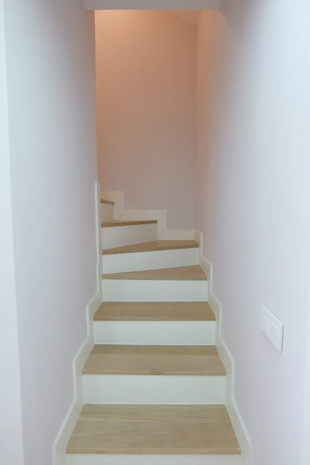 Escalera interior con peldaños de madera y paredes blancas