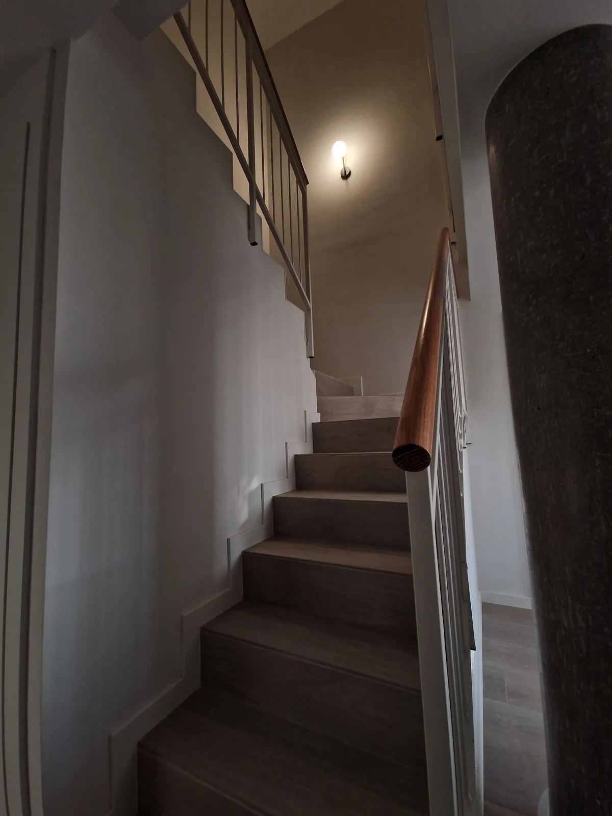 Escalera interior revestida con barandilla y aplique de pared