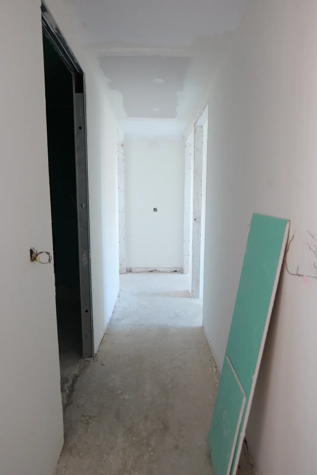 Pasillo con nuevos tabiques y techo de placa de yeso en fase de emplastecido