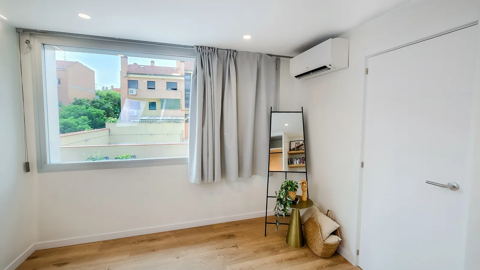 Segundo dormitorio con ventana amplia, suelo laminado de madera clara y aire acondicionado