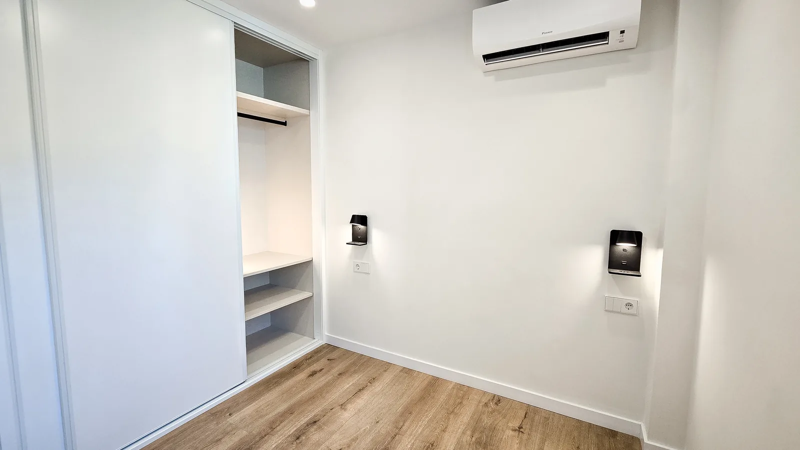 Segundo dormitorio con armario empotrado de puertas correderas y apliques de lectura