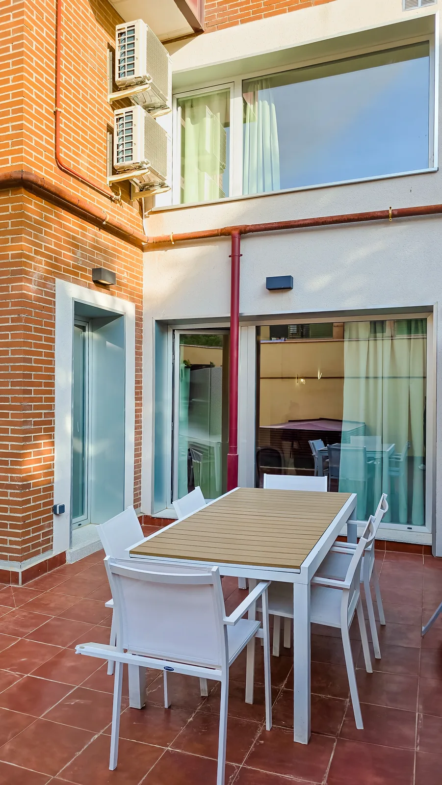 Patio antes de instalar la tarima, con suelo cerámico y mesa exterior junto a la fachada