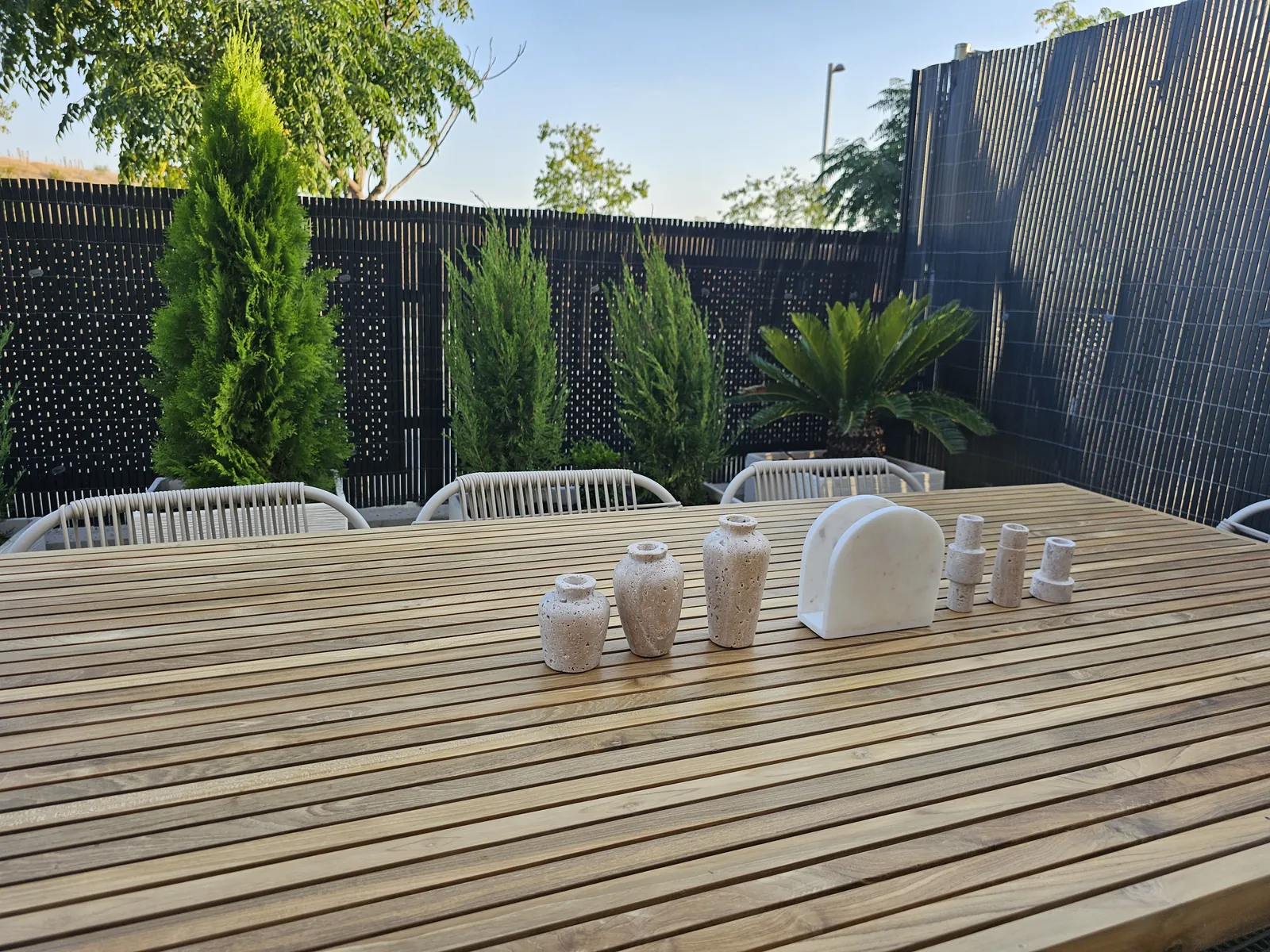 Mesa de madera exterior junto a plantas y valla de ocultación en el patio