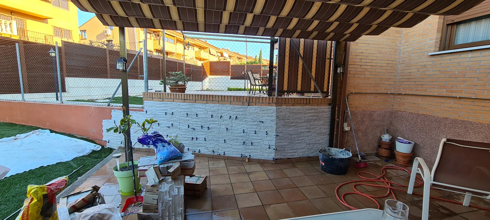 Patio durante la obra con el murete revestido y materiales en el suelo