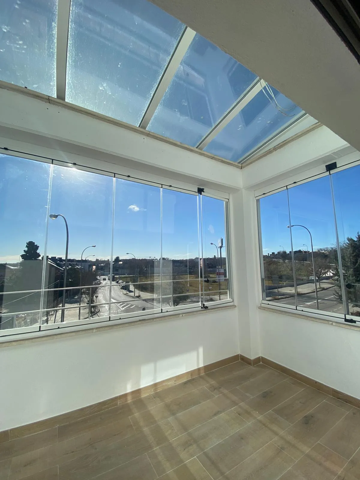 Terraza acristalada con techo de vidrio y suelo de madera